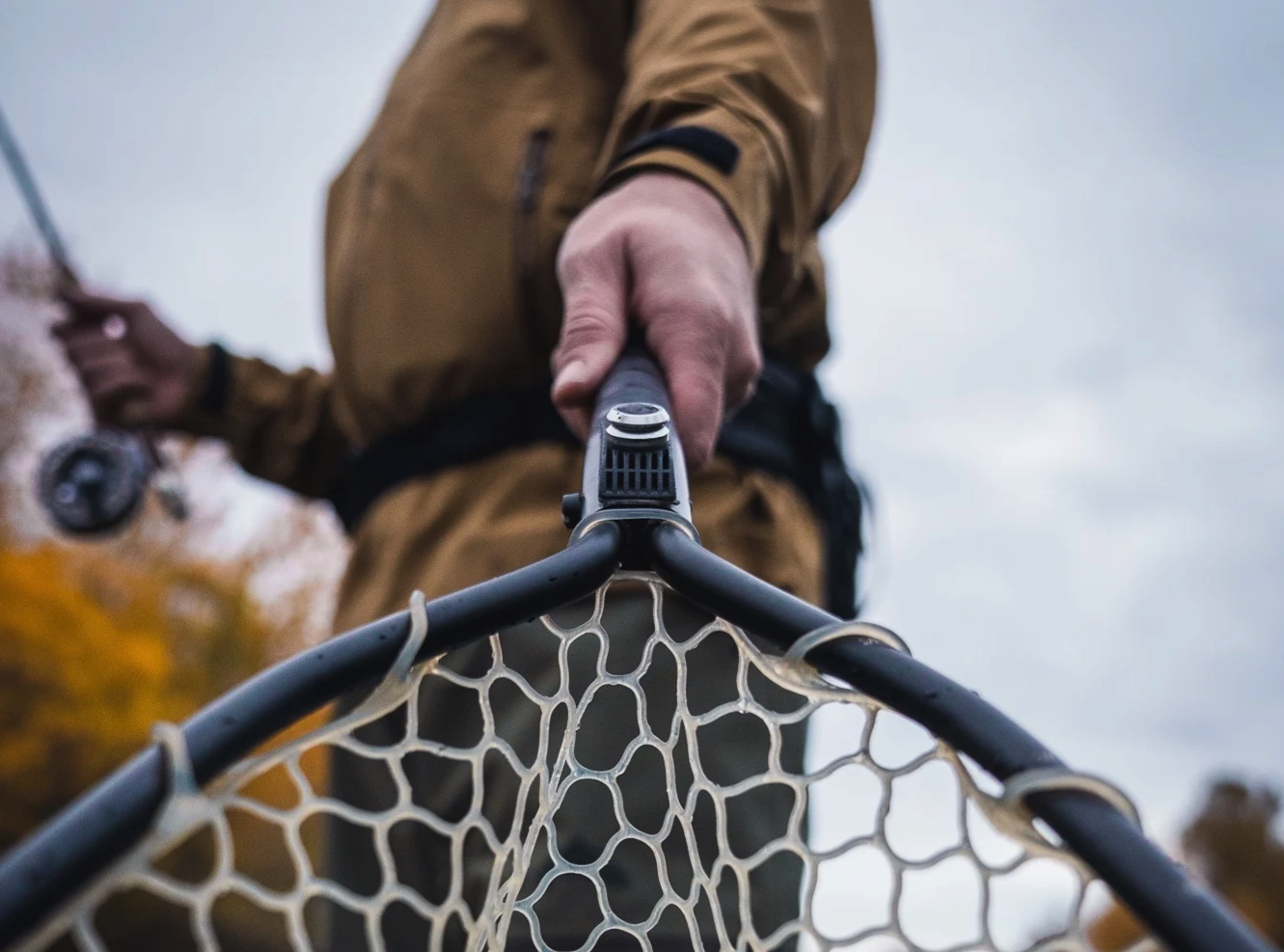 Angler holding a landing net with Broder Net Clip Extra Mount attached for quick magnetic net connection