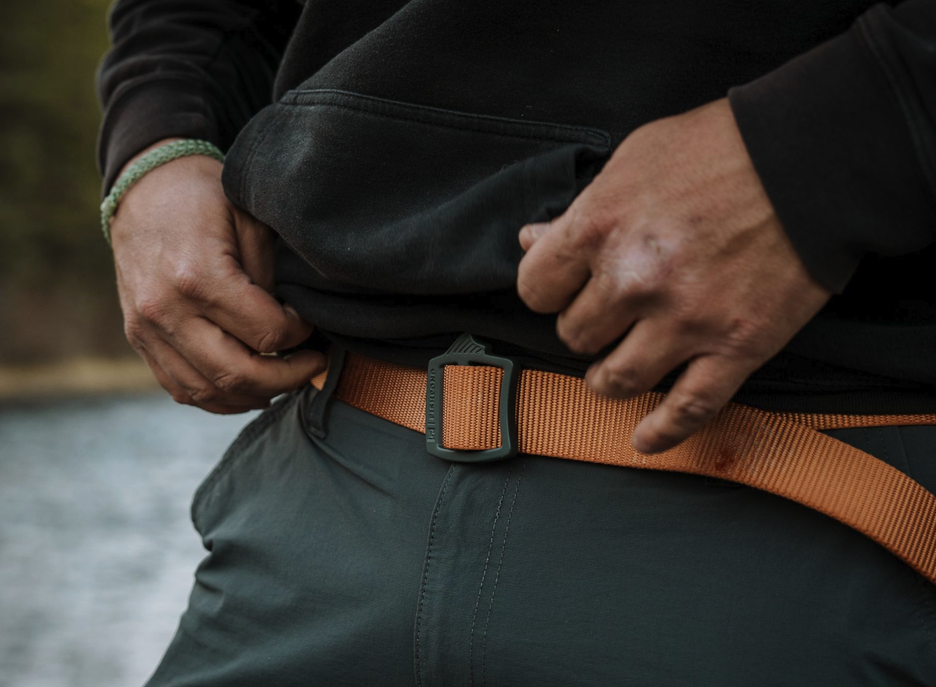 Man near river adjusting orange Fishpond Dorsal Fin Webbing Belt