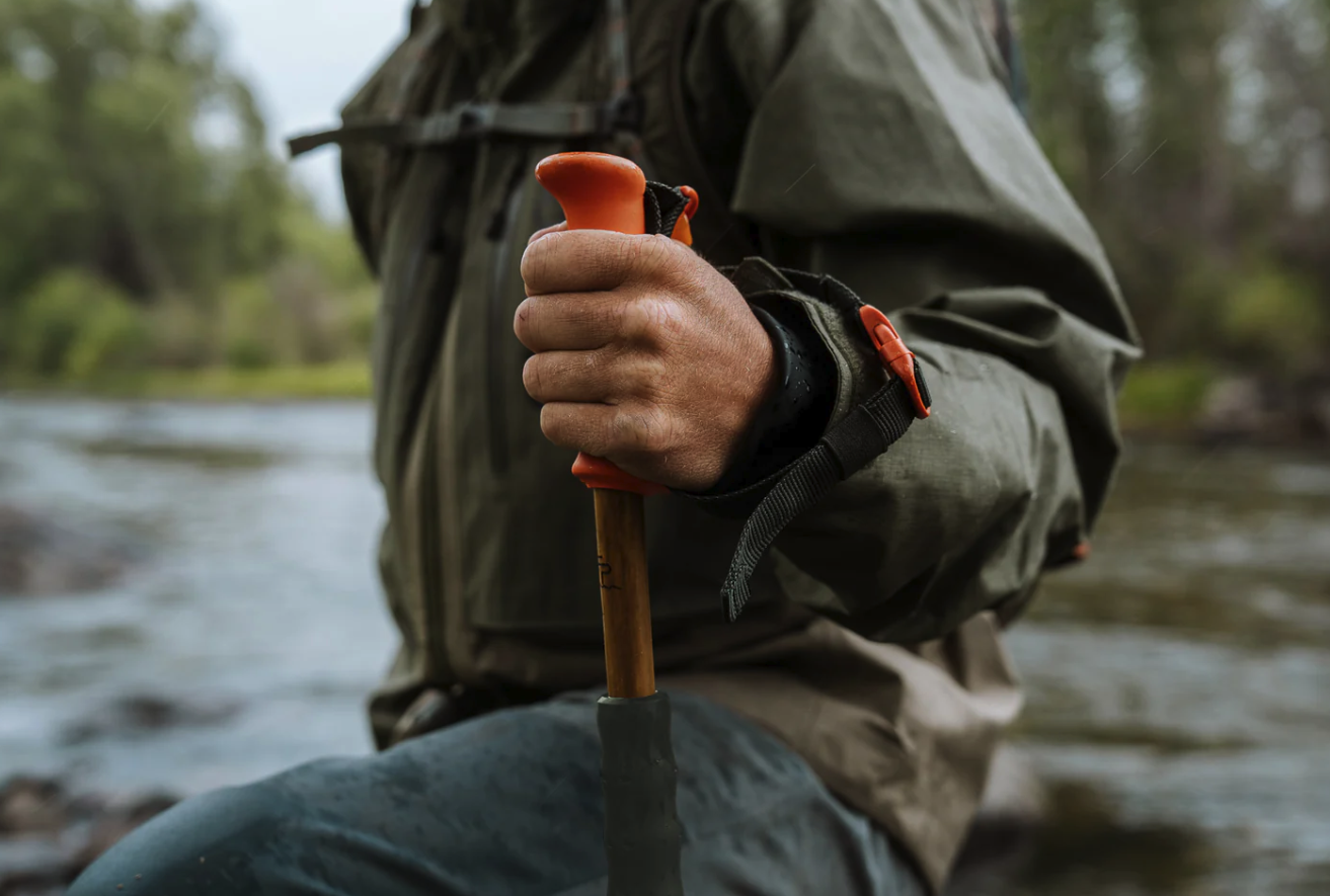 Wading angler holding handle of Fishpond Grass Sticks Wading Staff