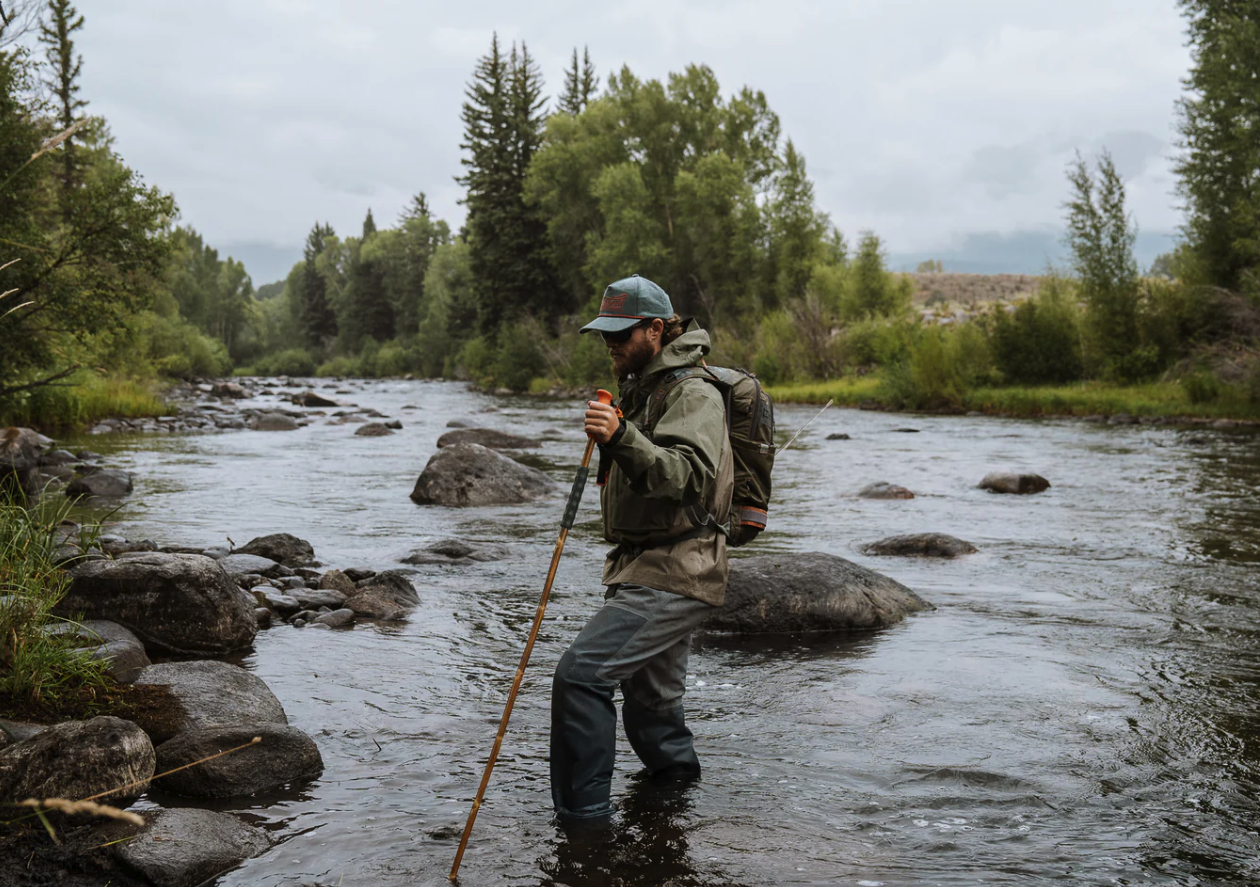 Angler walking across river with Fishpond Grass Sticks Wading Staff