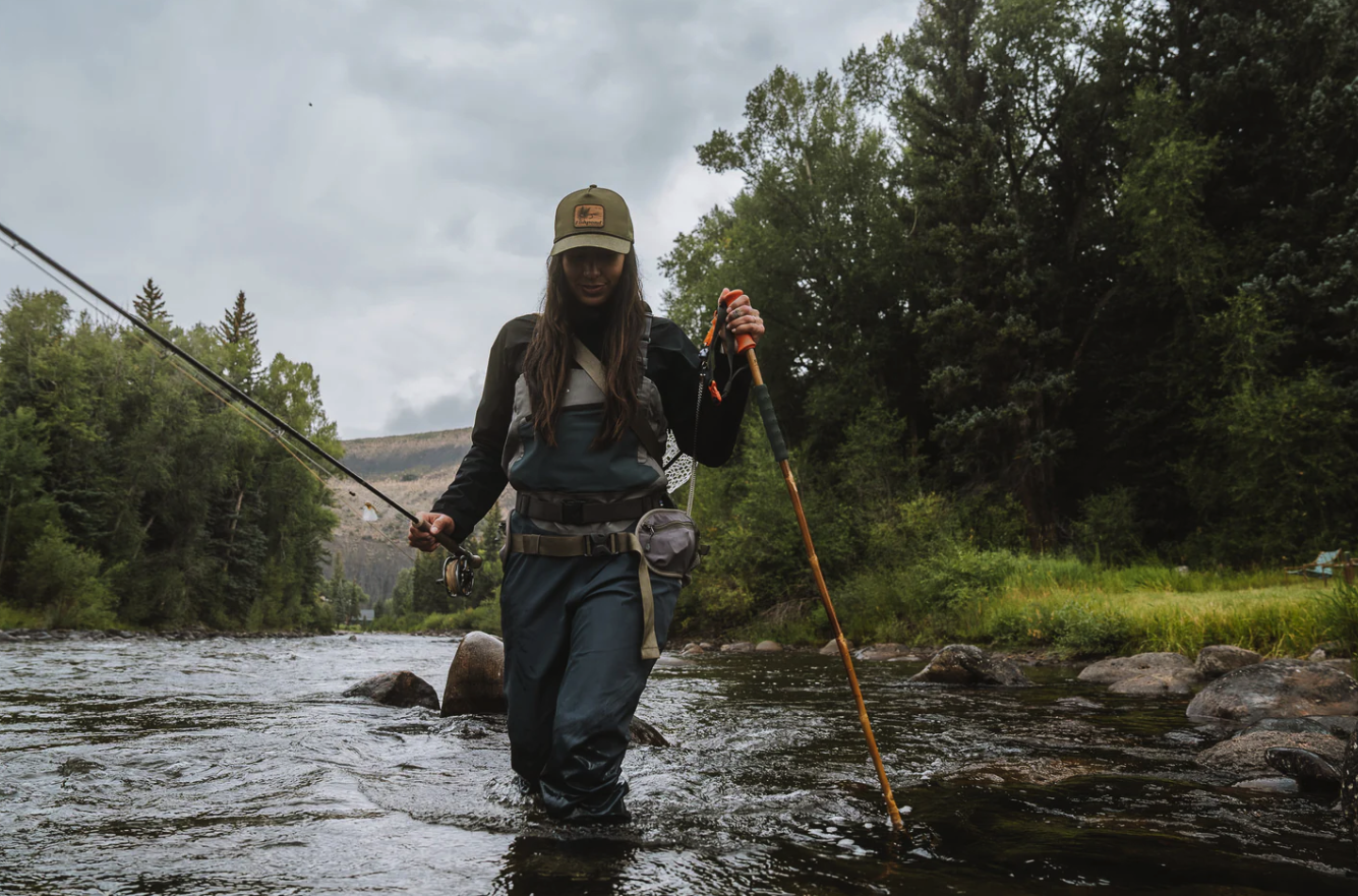 Female fly fisher walking in river with Fishpond Grass Sticks Wading Staff