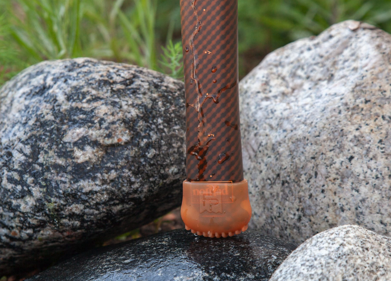 Fishpond Nomad Net End Cap Cutthroat Orange on net by rocks