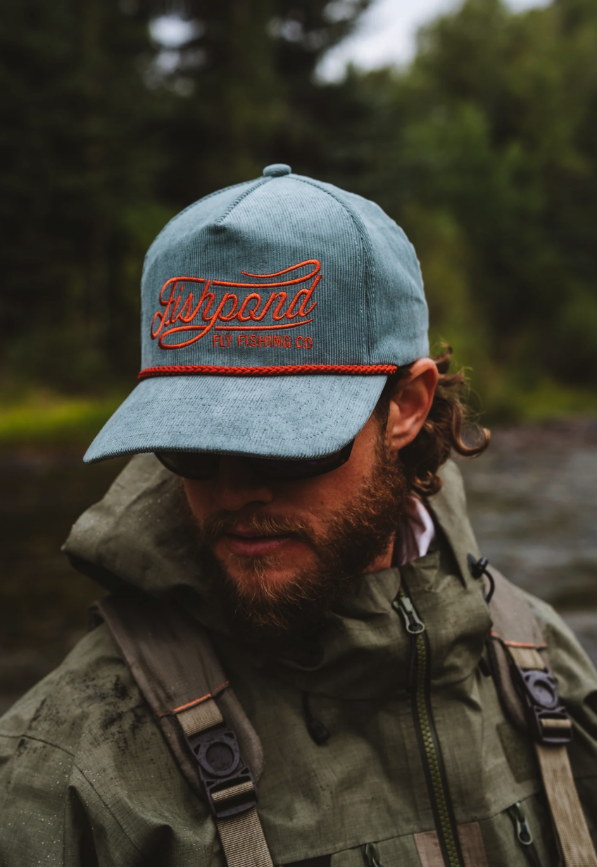 Fly angler in rain jacket on river wearing Fishpond Heritage Corduroy Hat Tempest
