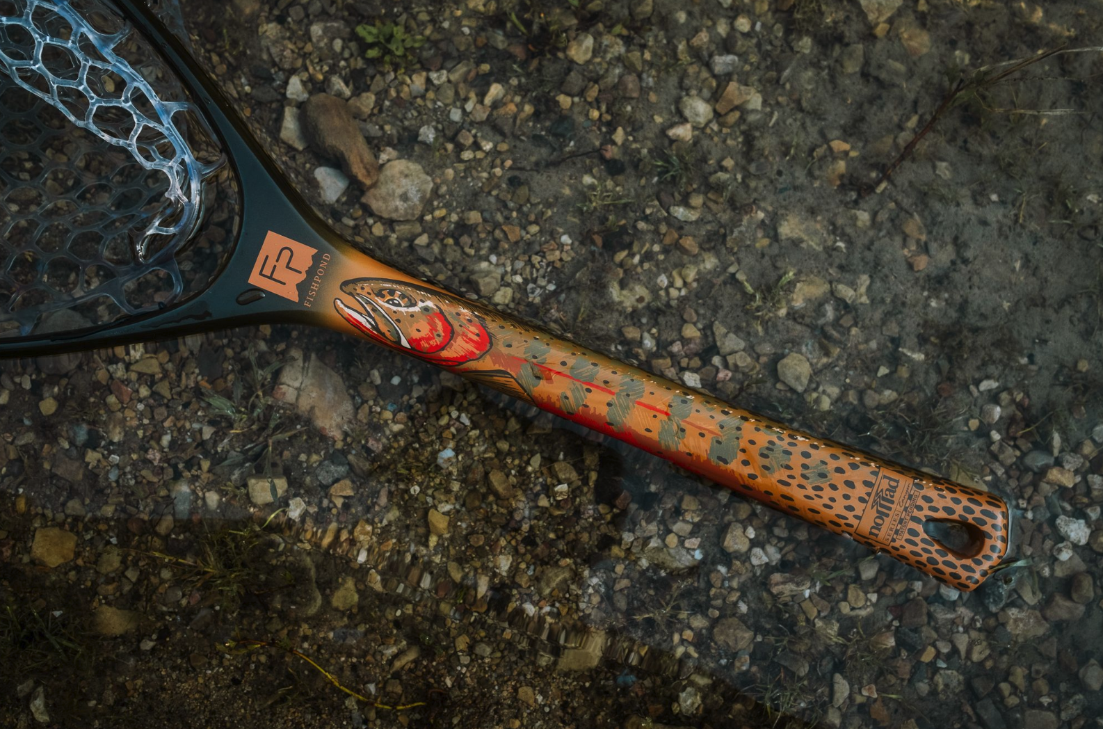 Fishpond Nomad Canyon Net Colorado Cutty edition lying in river.