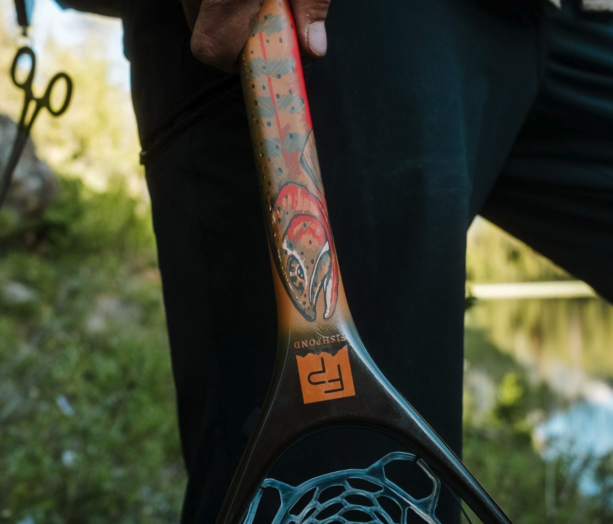 Man holding handle of Fishpond Nomad Canyon Net Colorado Cutty edition