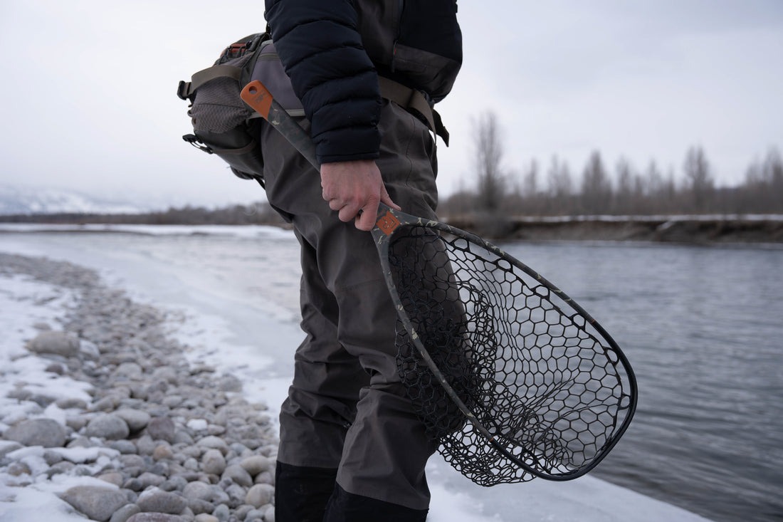 Angler carrying Fishpond Nomad Emerger 2.0 fly fishing net while wading river