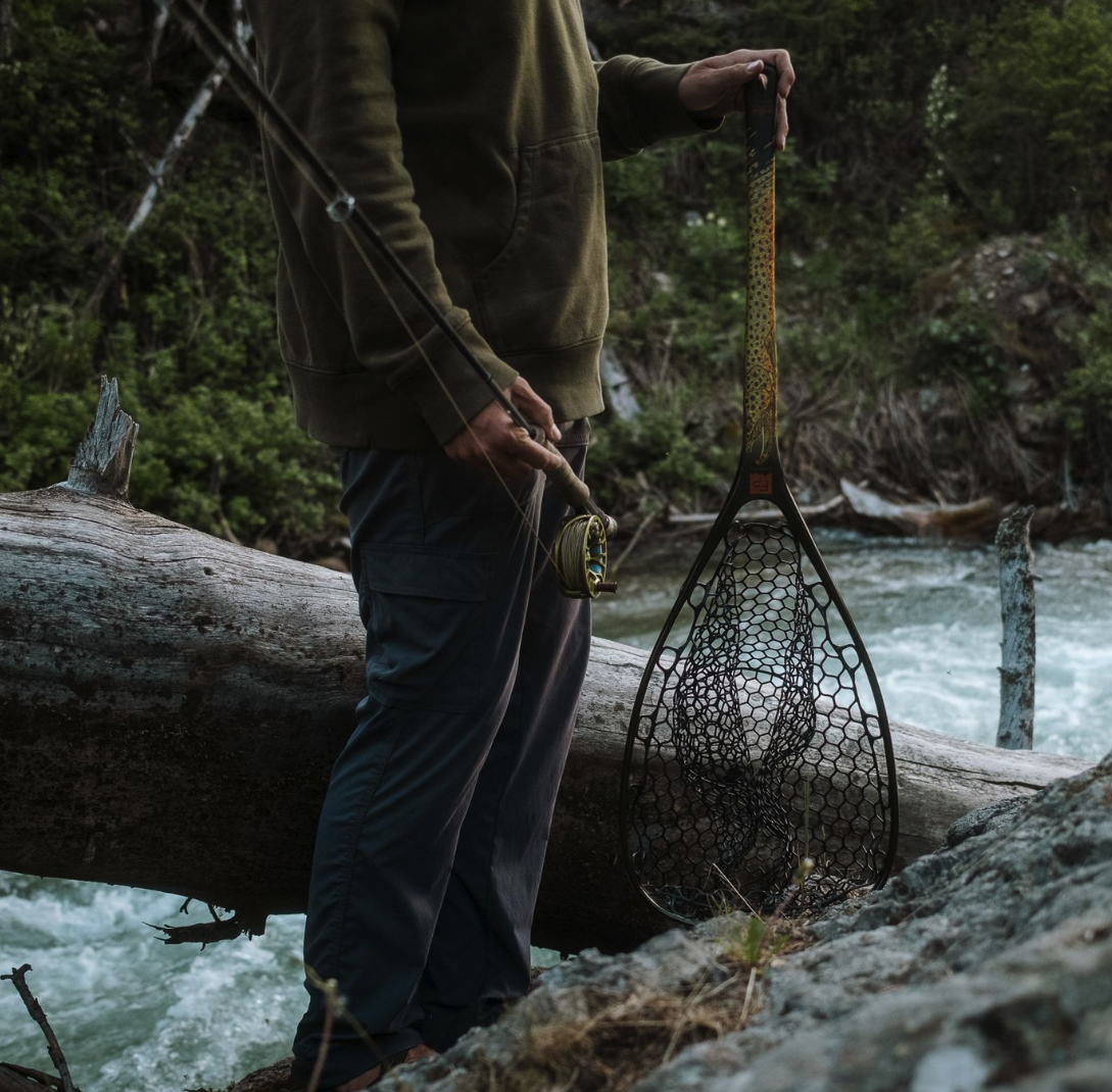 Angler holding Fishpond Nomad Middle Fork Net Hook Jaw Limited Edition by river