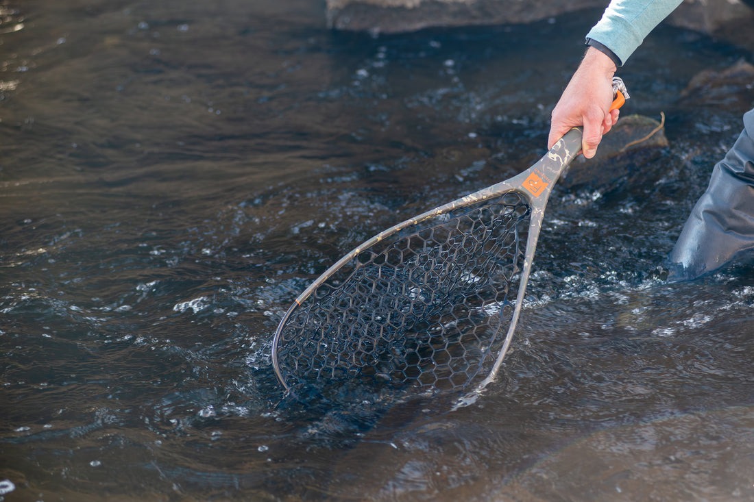 Lightweight Fishpond camo trout landing net in use on rocky river