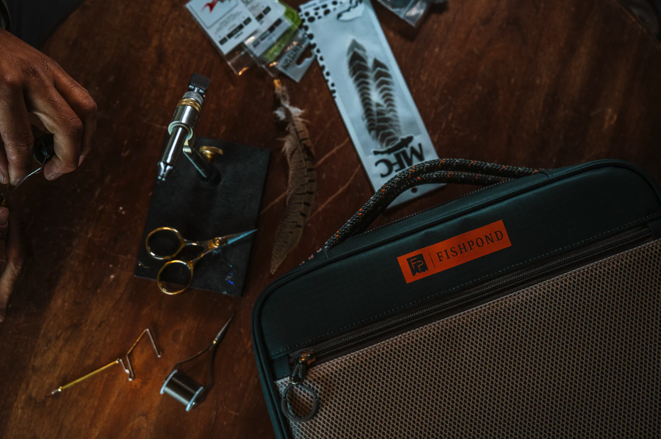 Fishpond Backwater Fly Tying Kit on desk with fly tying tools and materials