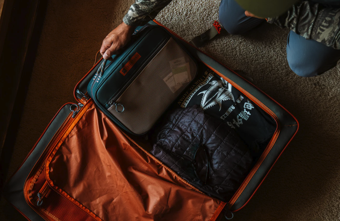 Man packing Fishpond Backwater Fly Tying Kit into luggage