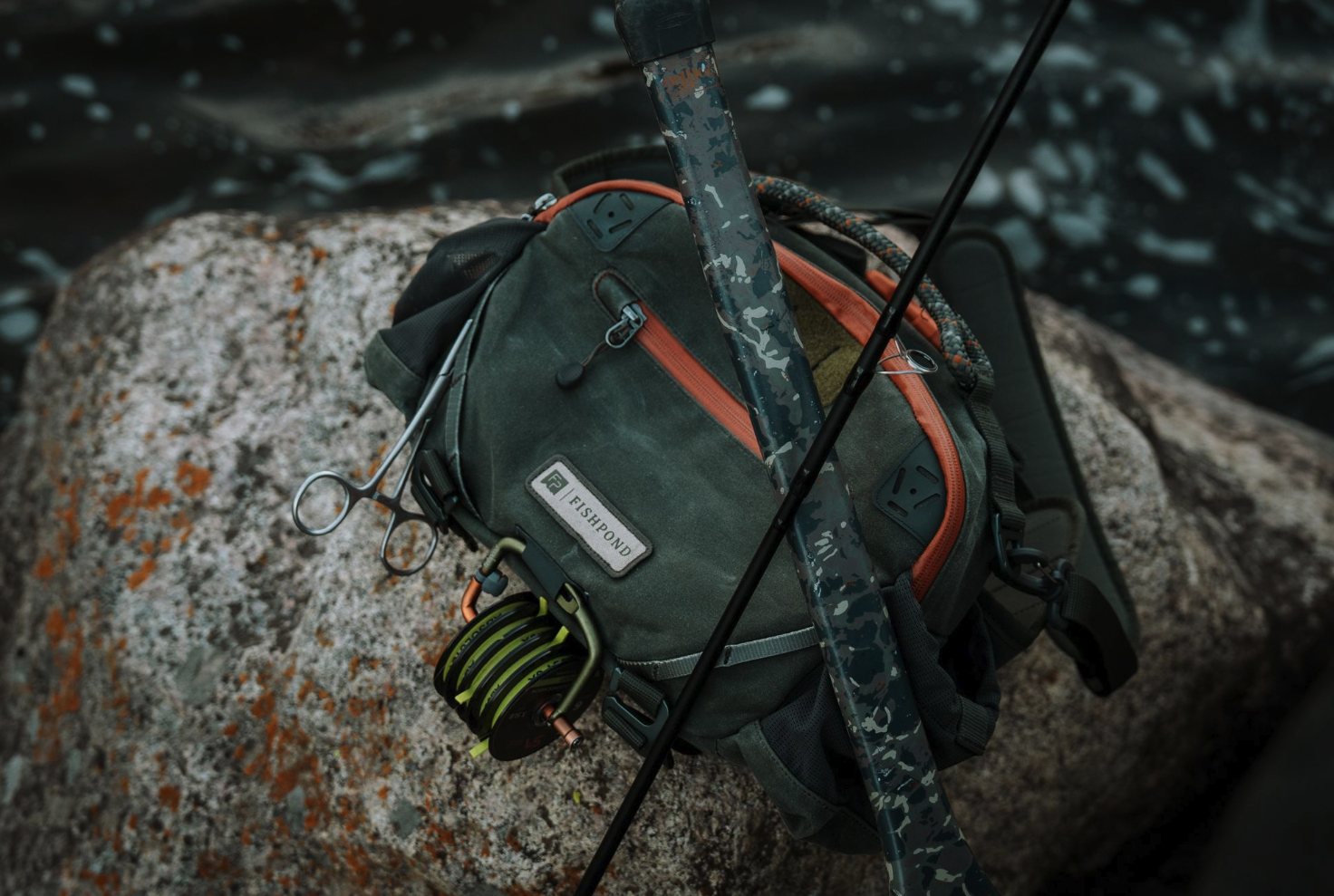 Fishpond Elkhorn Lumbar Pack Duskwood Waxed Cotton on rock with net and rod