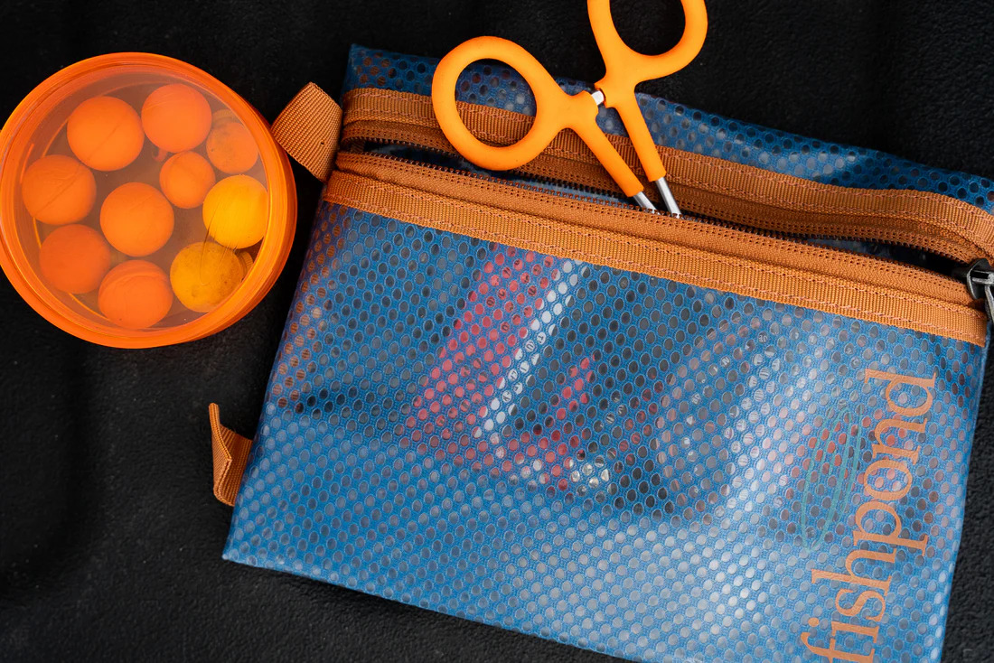 Different items being shown stored in the Fishpond Sandbar Travel Pouches