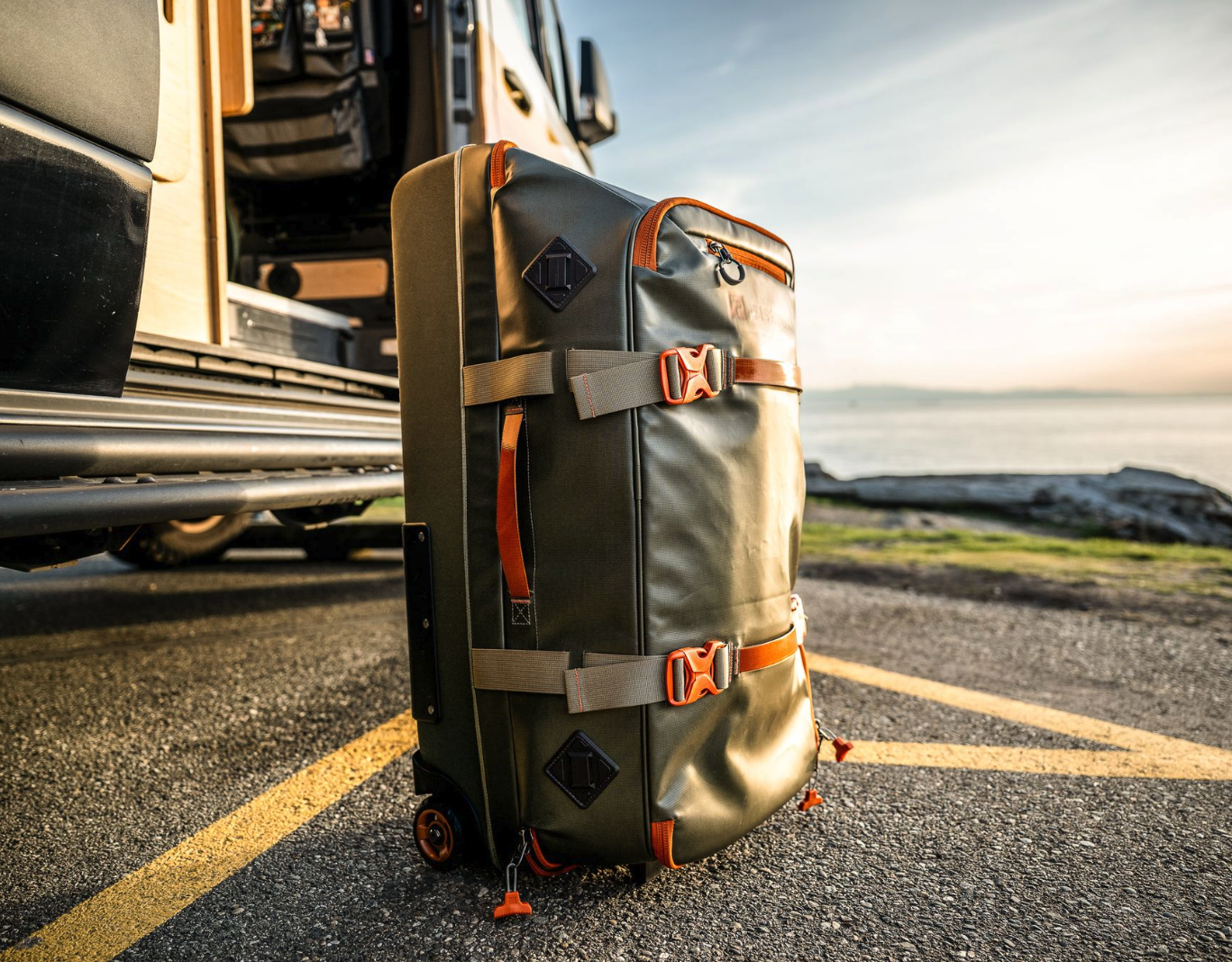 Side view of Fishpond Stormshadow Medium Rolling Duffel by ocean