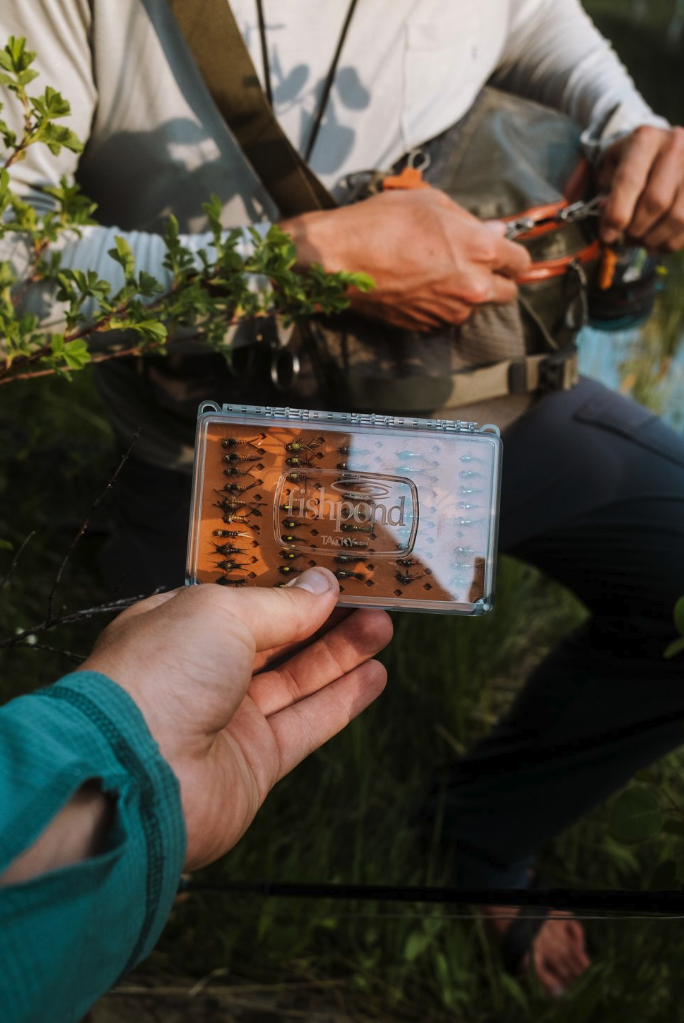 Angler handing  Tacky Day Pack Fly Box Burnt Orange color to another