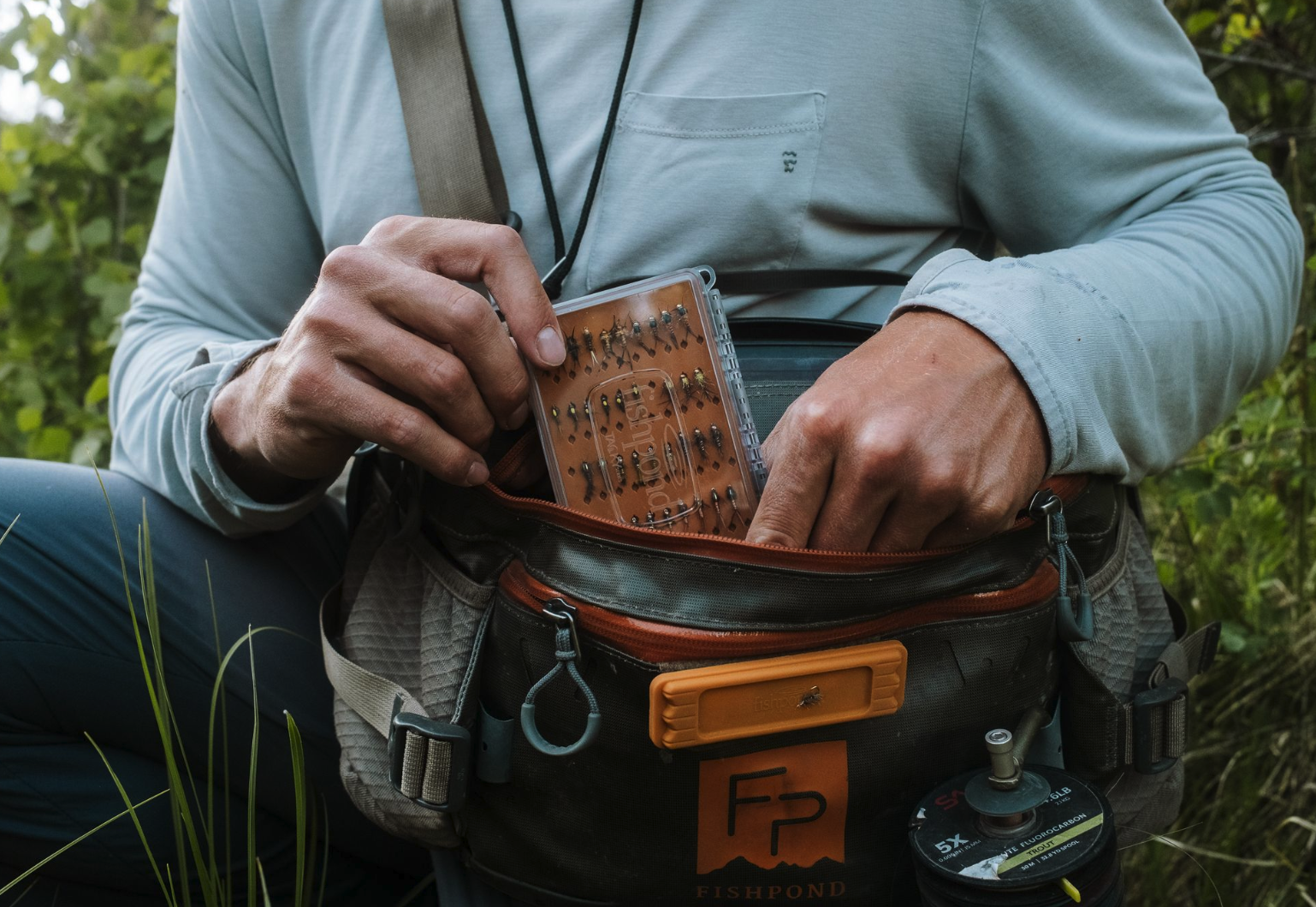 Angler putting  Tacky Day Pack Fly Box Burnt Orange into hip pack