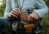Angler putting  Tacky Day Pack Fly Box Burnt Orange into hip pack