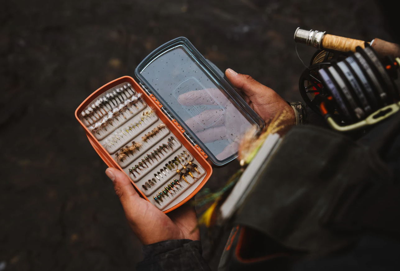Man fishing looking in Fishpond Tacky Pescador Clear Lid Fly Box Medium full of flies