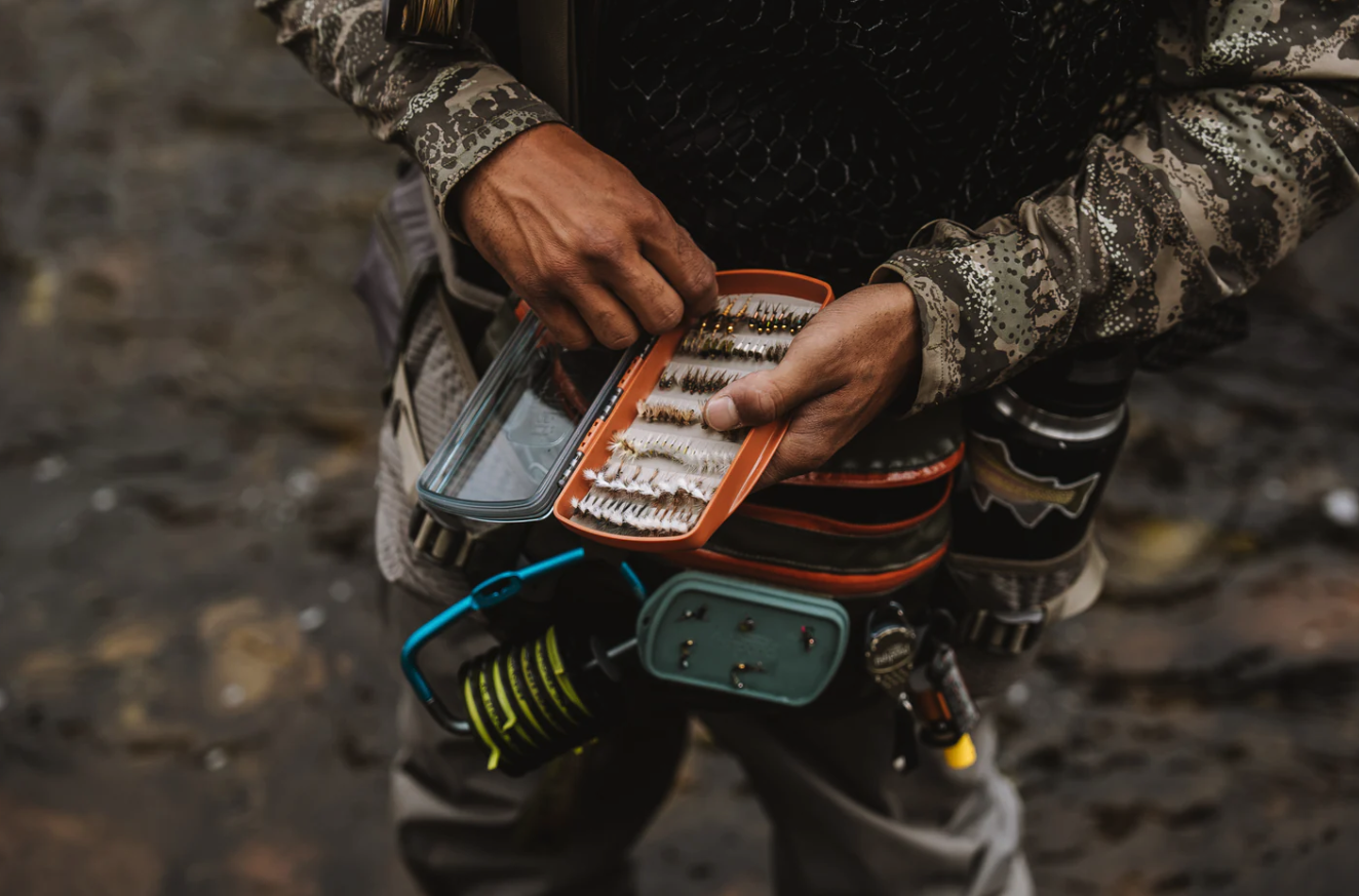 Angler selecting a fly from Fishpond Tacky Pescador Clear Lid Fly Box Medium