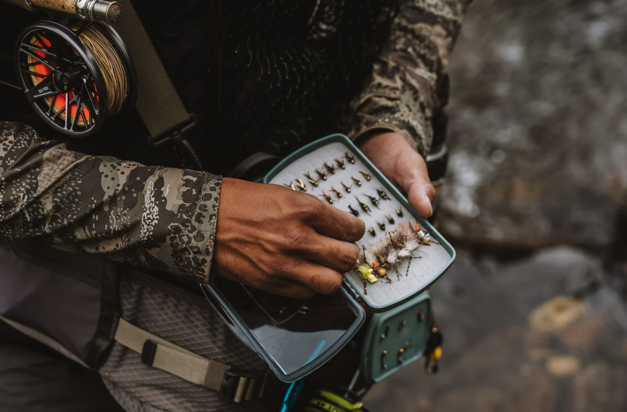 Angler selecting flies from Fishpond Tacky Pescador Dynamic Foam Clear Lid Fly Box Medium