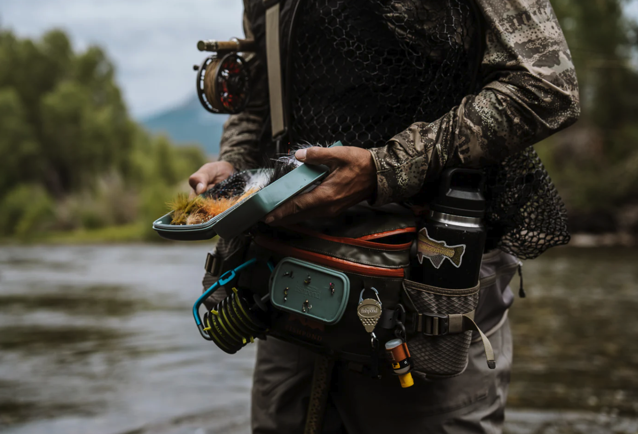 Angler selecting a fly from Fishpond Tacky Pescador Dynamic Foam Fly Box Large while in river