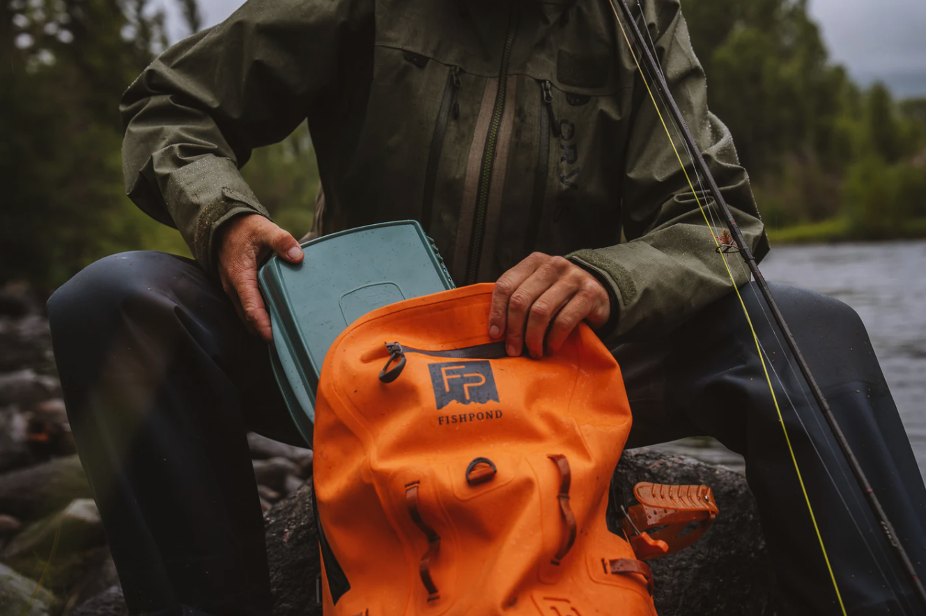 Angler putting Fishpond Tacky Pescador Dynamic Foam Fly Box XL into backpack