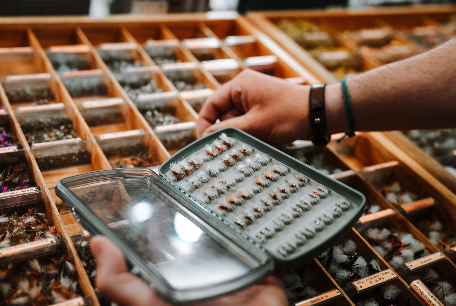 Man selecting flies to put into Fishpond Tacky Pescador LowPro Clear Medium Fly Box