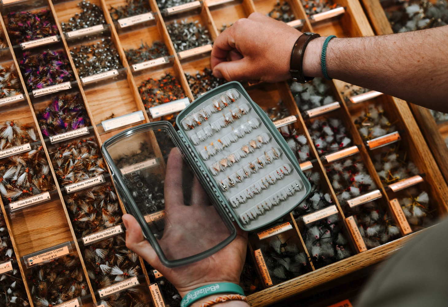Person holding Fishpond Tacky Pescador LowPro Clear Medium Fly Box in fly shop and selecting flies