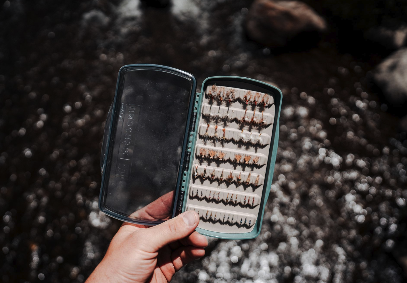 Fishpond Tacky Pescador LowPro Clear Medium Fly Box filled with flies and open near river