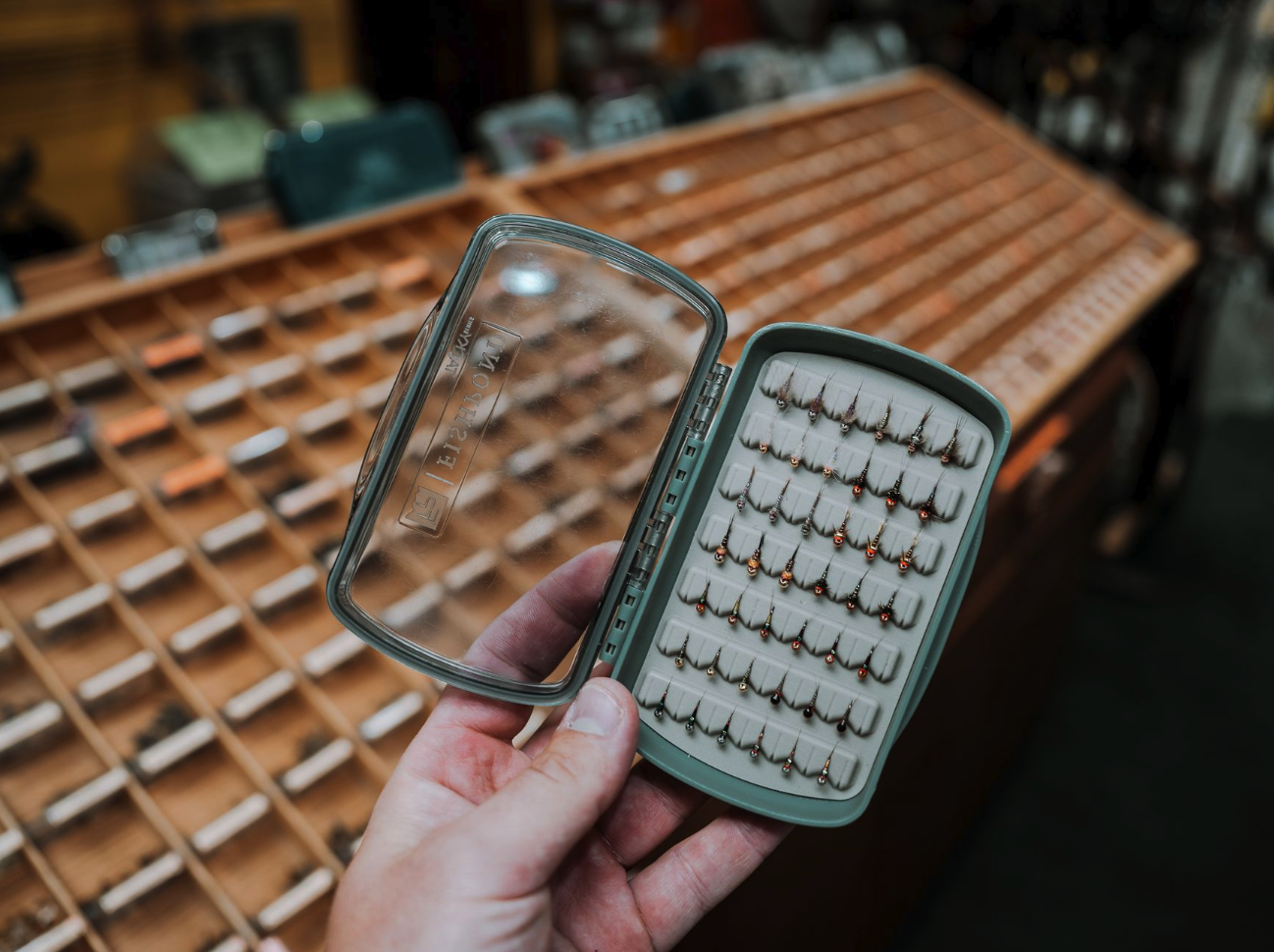 Fishpond Tacky Pescador LowPro Clear Small Fly Box held open in fly shop by fly bins