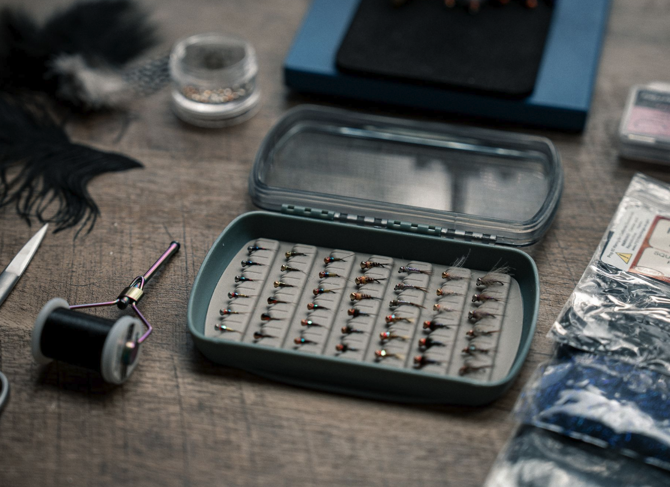 Fishpond Tacky Pescador LowPro Clear Small Fly Box filled with flies on tying desk by tools
