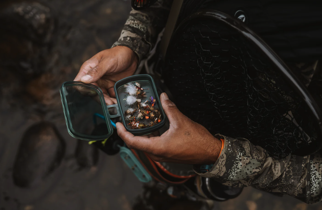 Angler holding open Fishpond Tacky Predator Fly Puck with trout flies