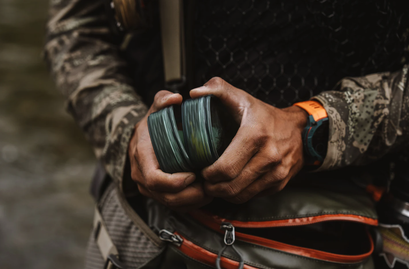 Angler holding stacked Fishpond Tacky Predator Fly Puck