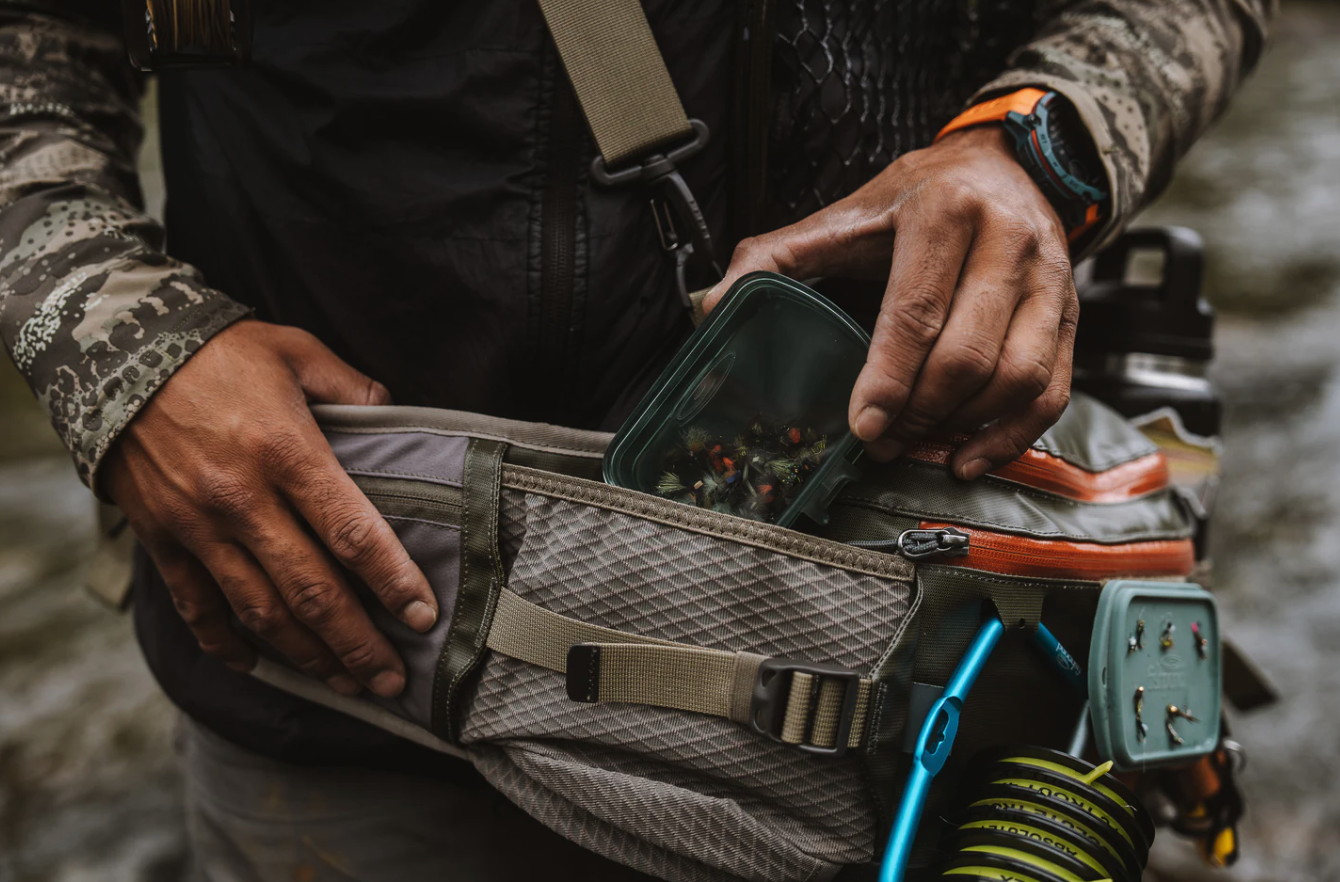 Fly fisherman putting Fishpond Tacky Predator Fly Puck into hip pack