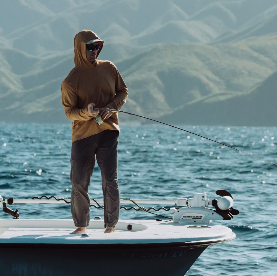 Angler fishing a fish on boat while wearing  Grundens Tough Sun Hoodie Whiskey color