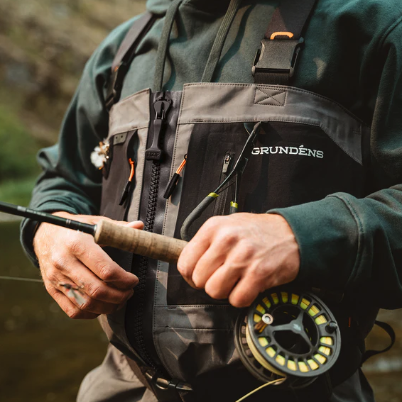Angler holding fly rod and reel while wearing Grundens Vector Zip Waders
