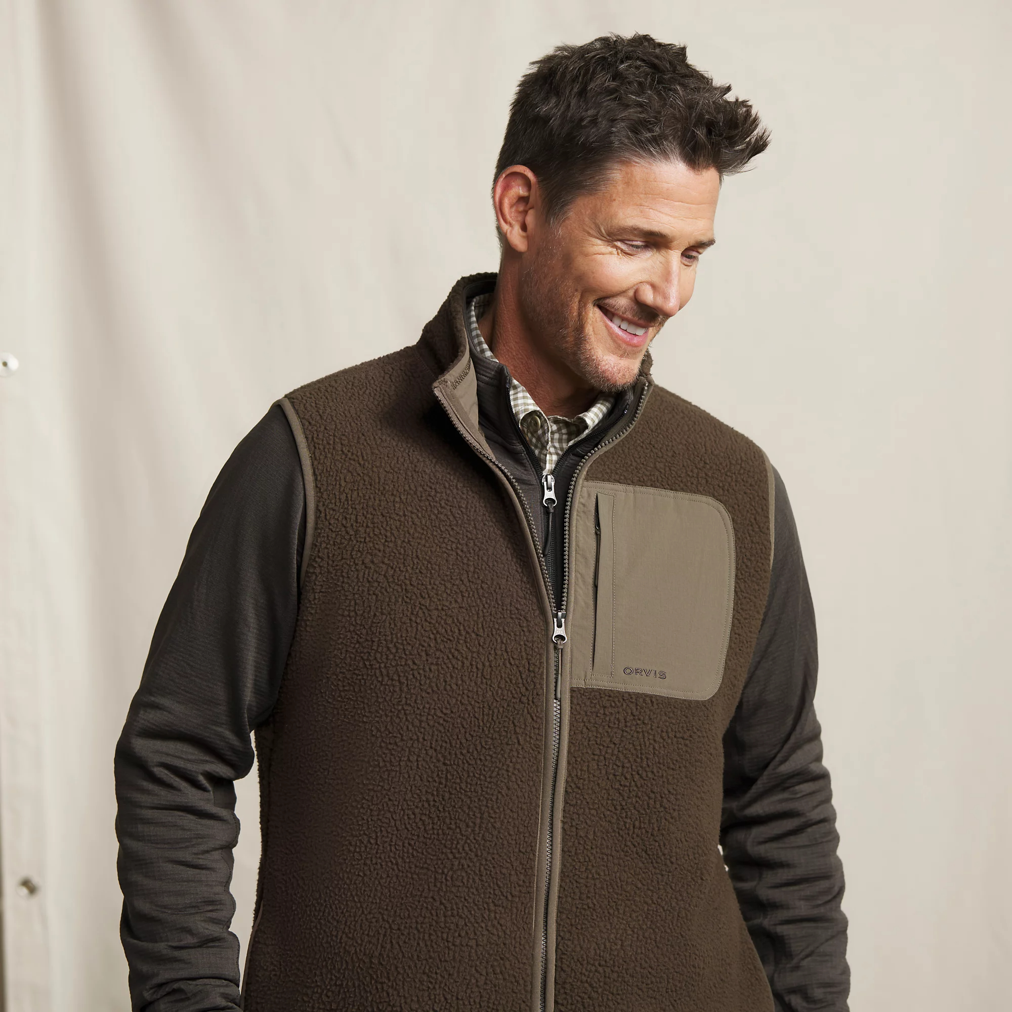 Close-up of Orvis Mad River men's sherpa fleece vest showing textured brown fleece, stand collar, and zippered chest pocket.