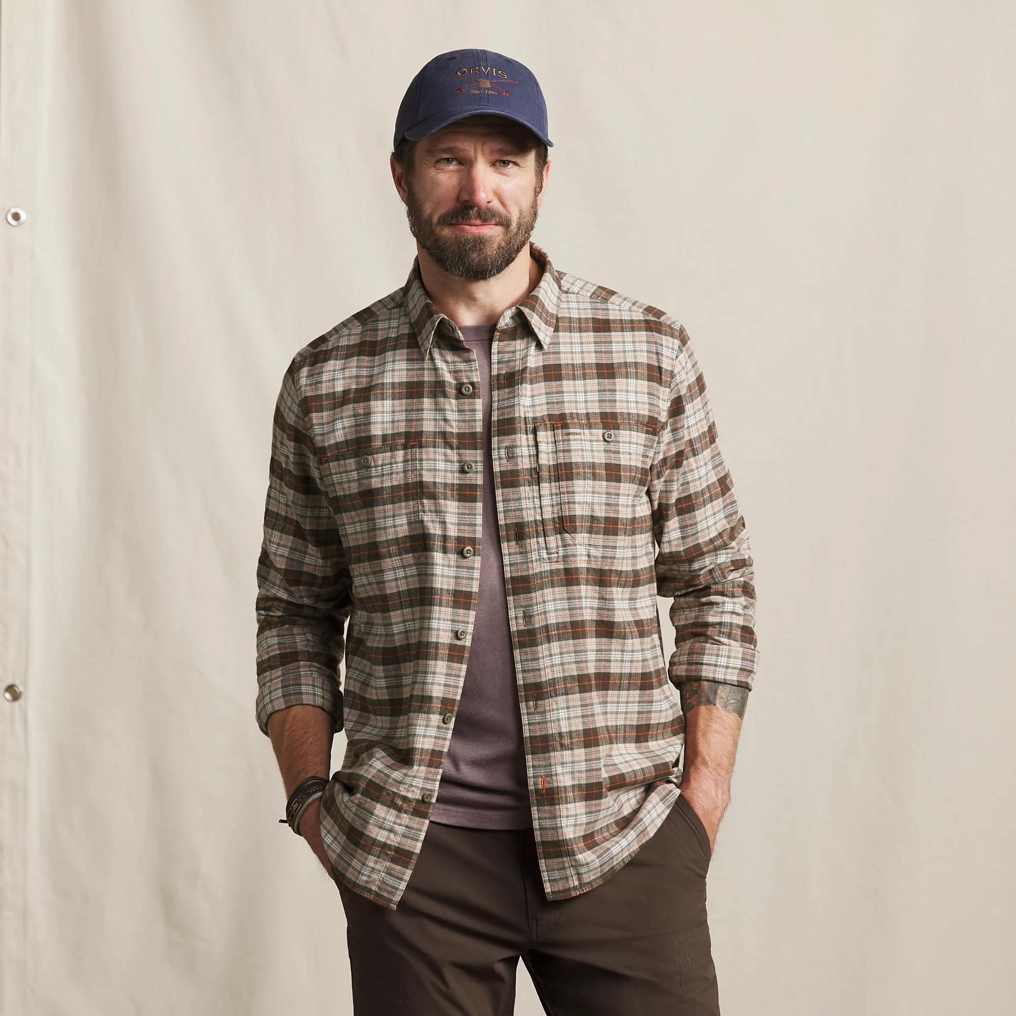 Man wearing Orvis Flat Creek Tech Flannel in neutral plaid, showing button front and two chest pockets.