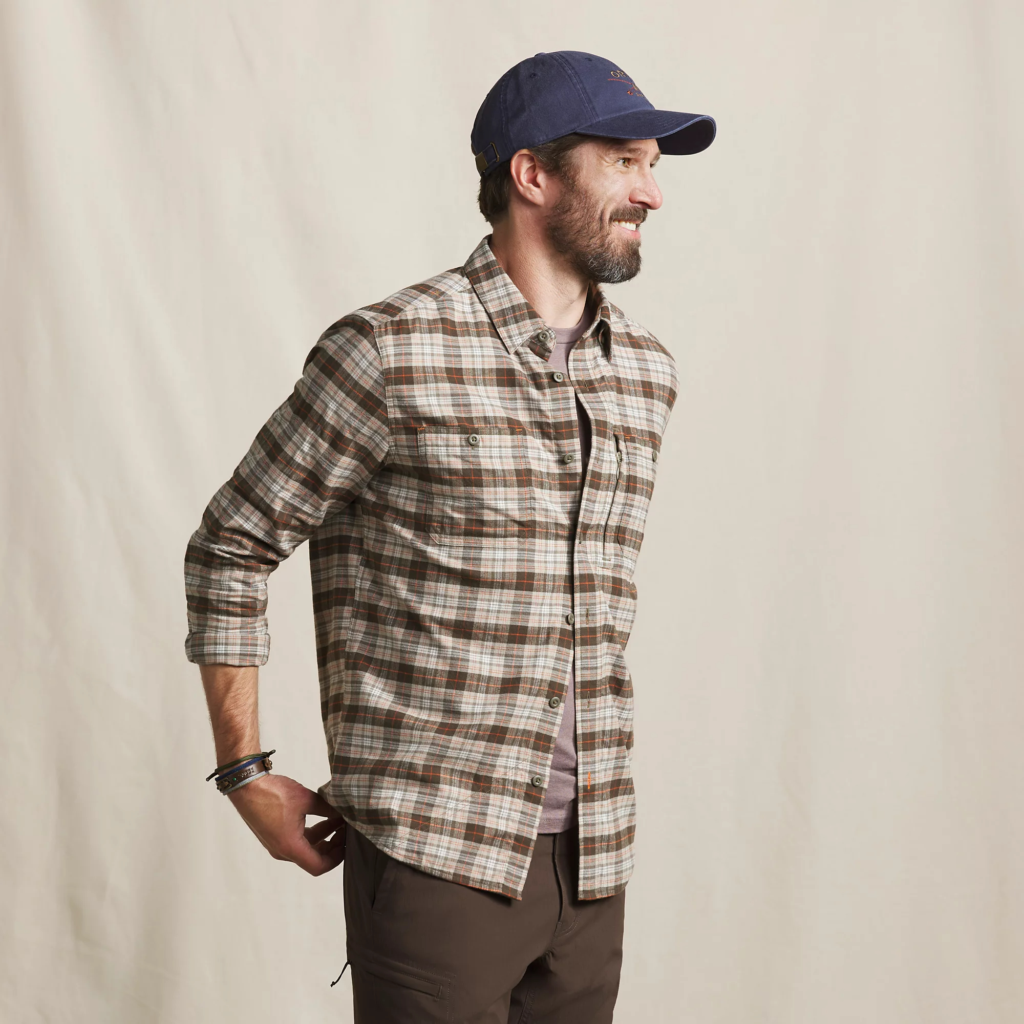 Side view of man wearing Orvis Flat Creek Tech Flannel in brown, cream, and gray plaid with rolled sleeves.