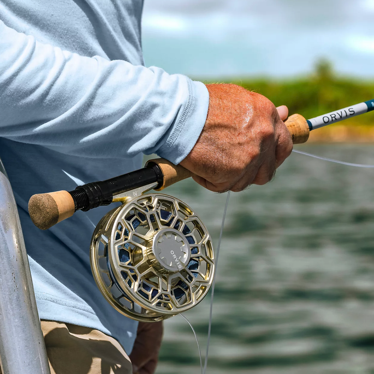 Angler holding rod with Orvis Ratio Fly Reel Gold color