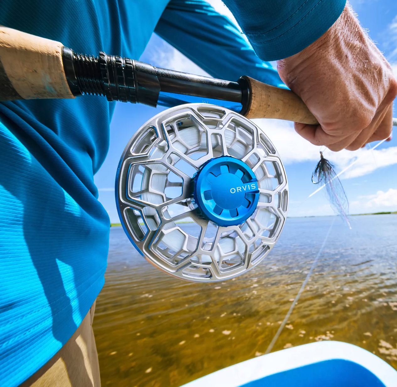 Angler holding rod with Orvis Ratio Fly Reel Silver Deep Sea color on boat