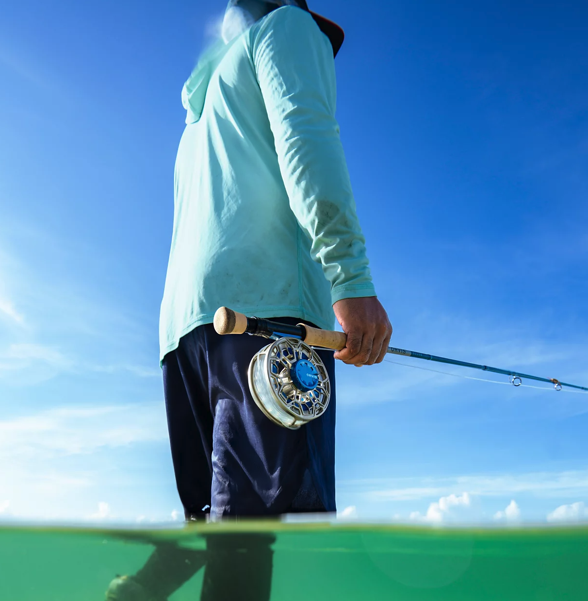 Angler wading and holding rod with Orvis Ratio Fly Reel Silver Deep Sea