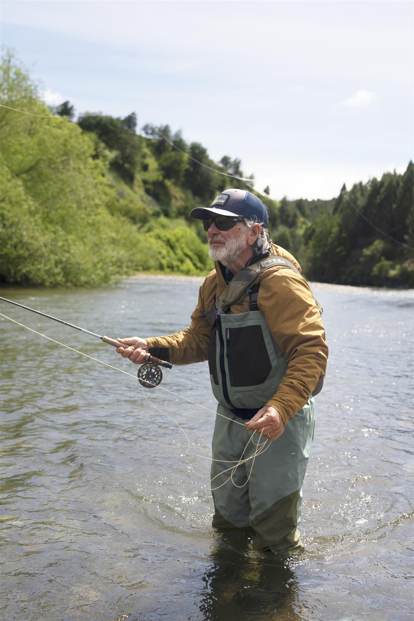 Fly fisherman wearing Orvis Clearwater Zip Waders while casting for trout in a clear mountain river