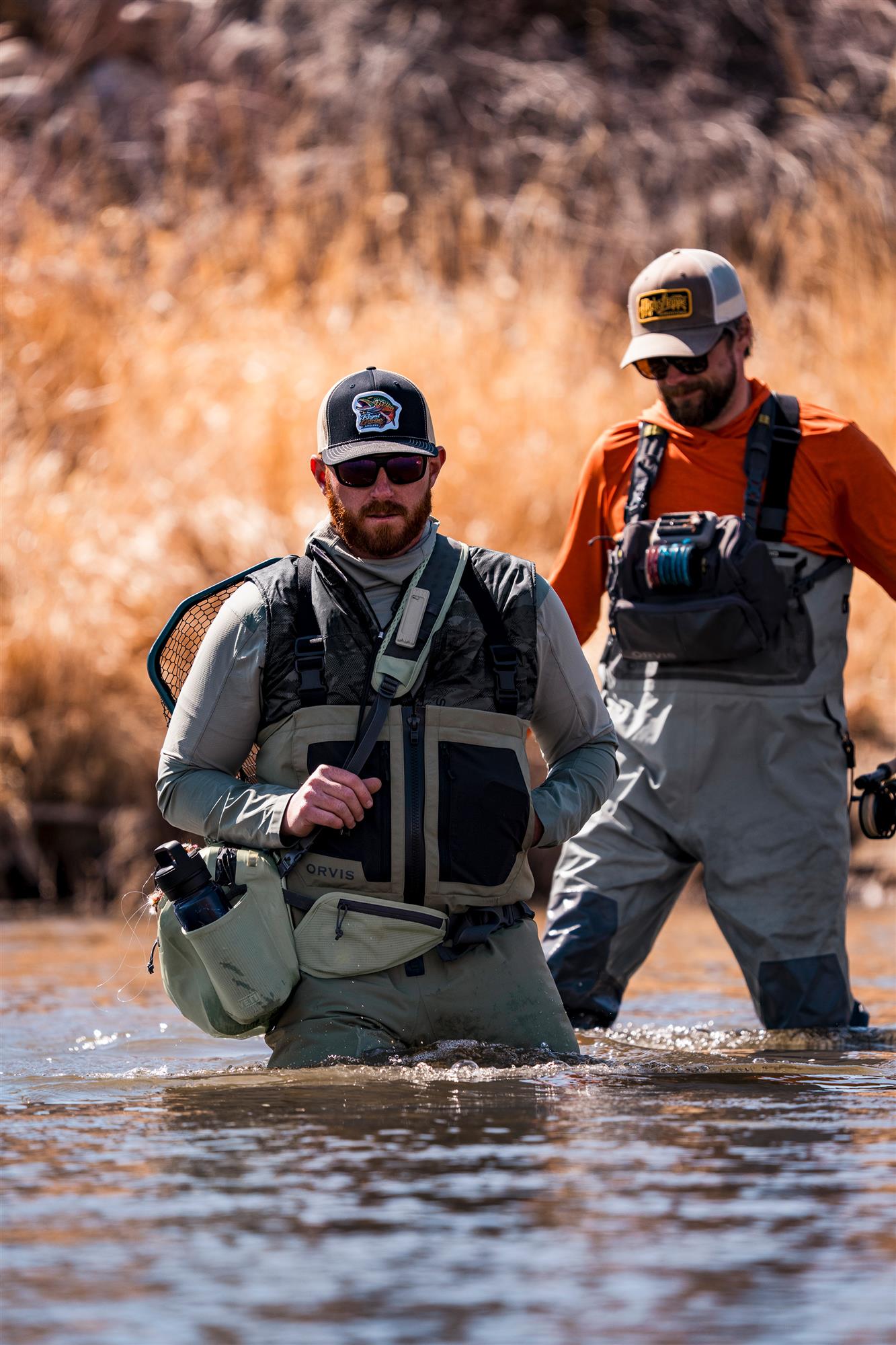Two fly anglers wearing Orvis Clearwater Zip Waders while wading a shallow river in cold-weather fishing conditions