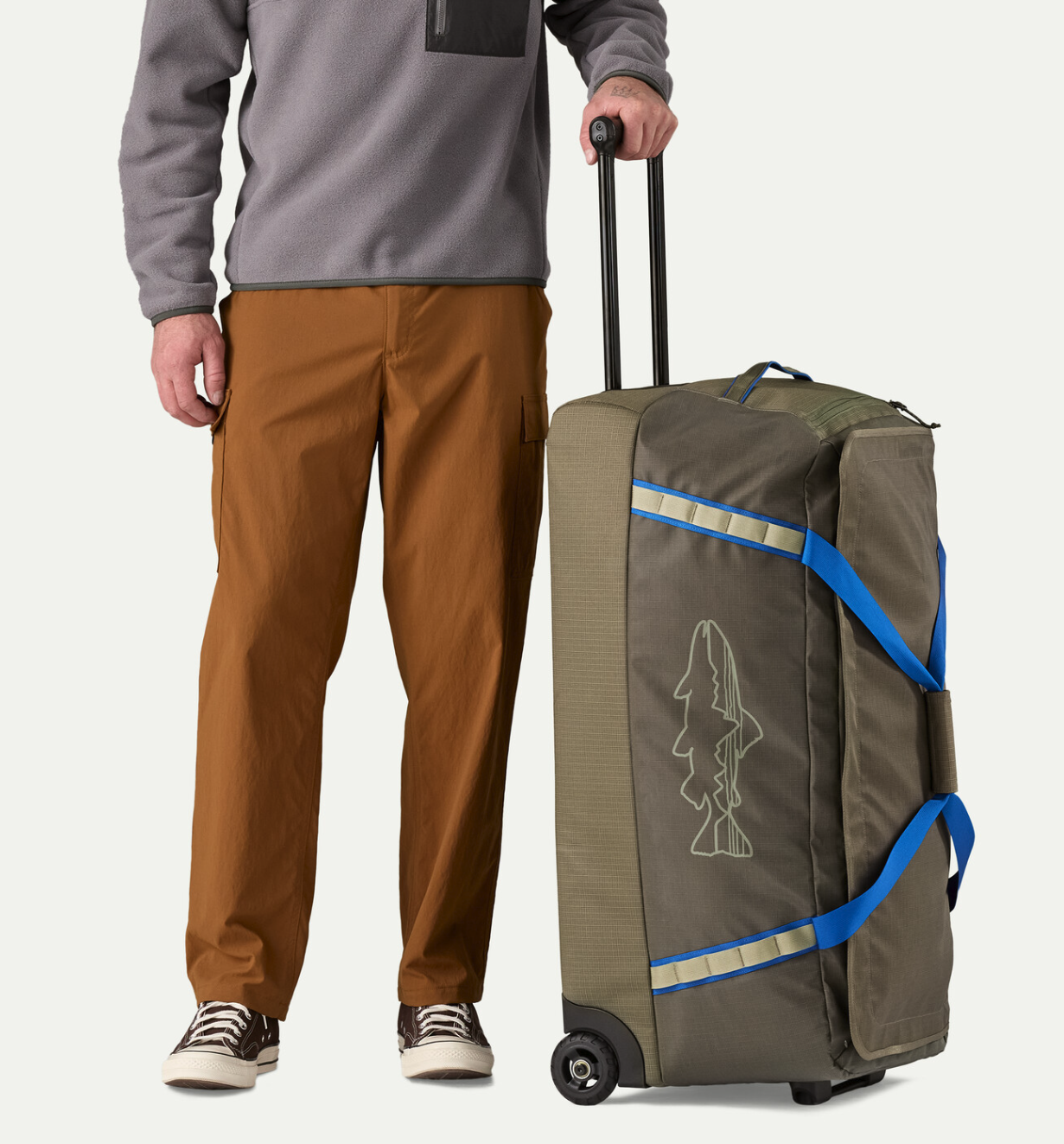 Man standing next to  Patagonia Black Hole Matte Wheeled Duffel 100L on bottom.