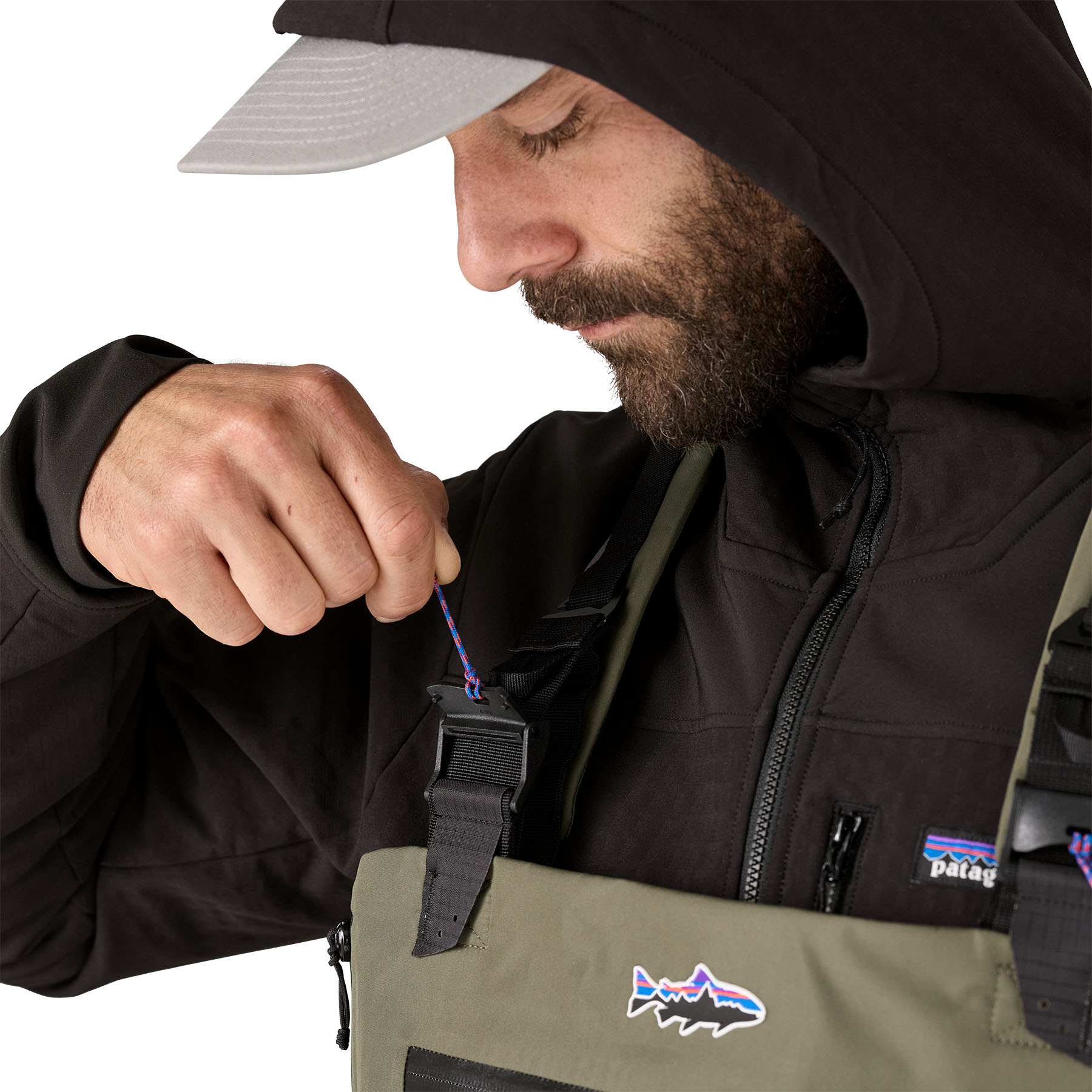 Model highlighting the clasp for Patagonia's Swiftcurrent Expedition Wader suspender system