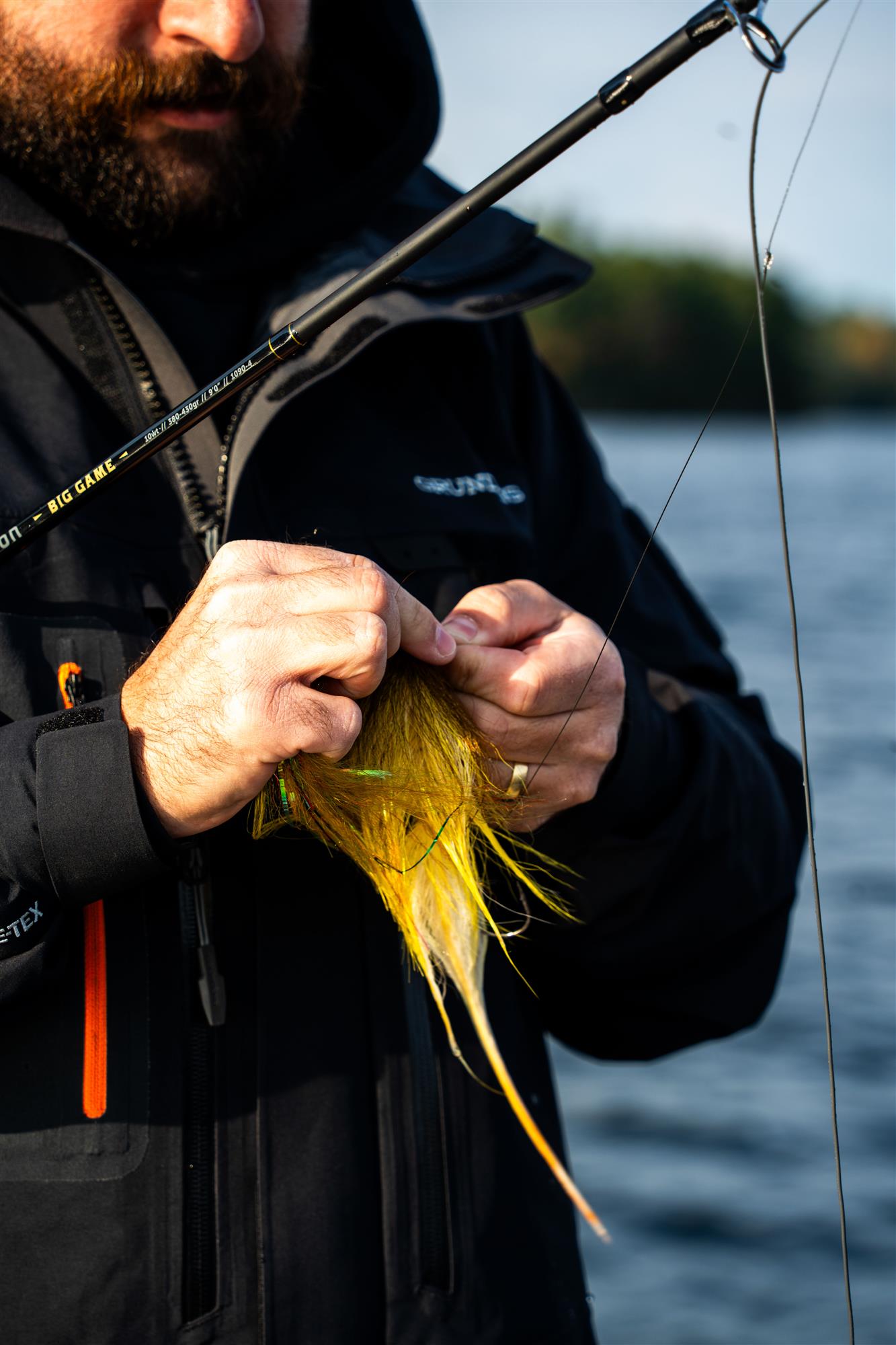 Angler holding Redington BIG GAME Fly Rod while tying fly on