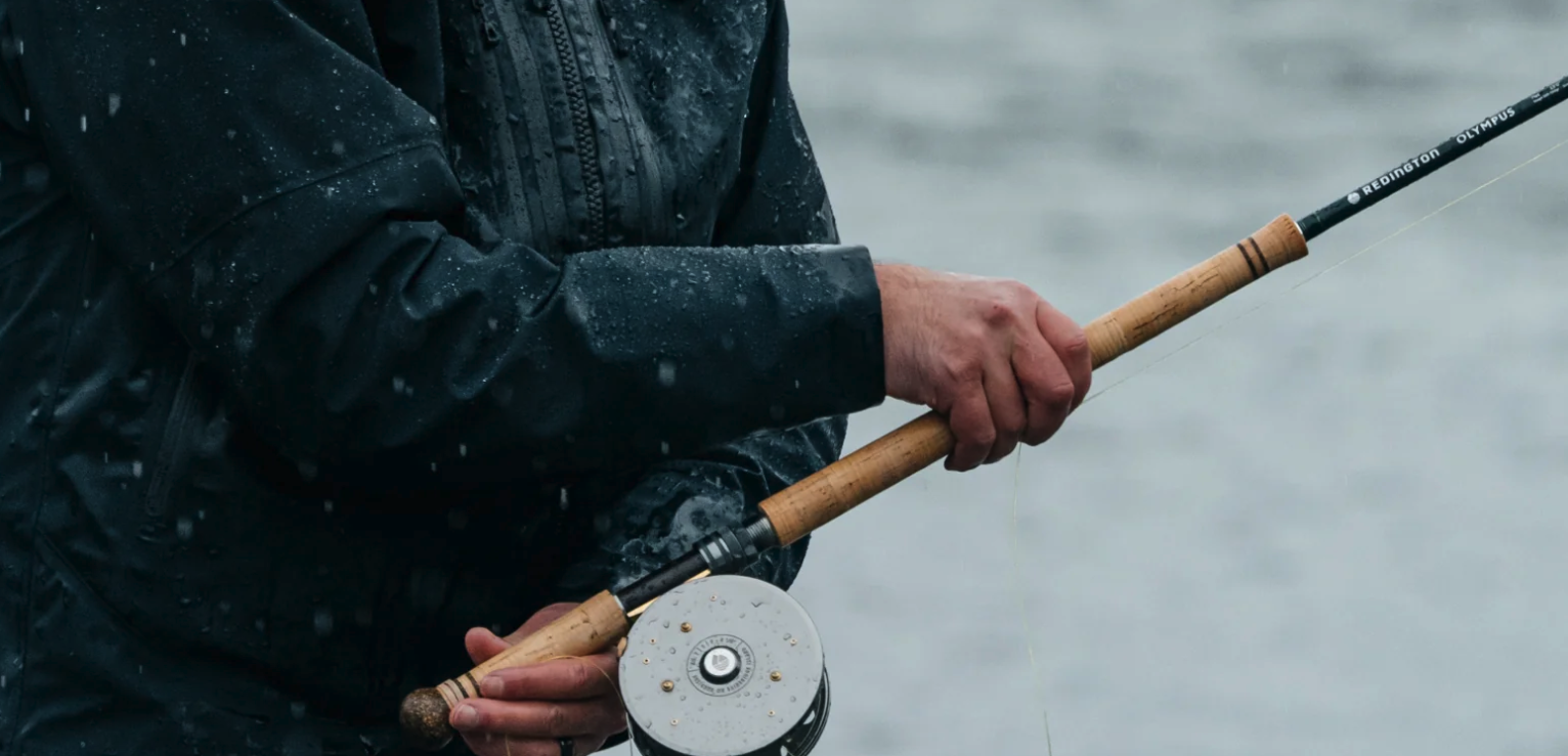Angler holding Redington Olympus Fly Rod with fly reel
