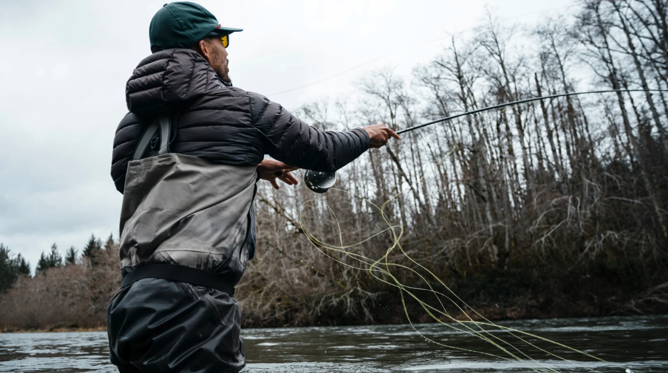 Wading angler casting Redington Olympus Fly Rod in river