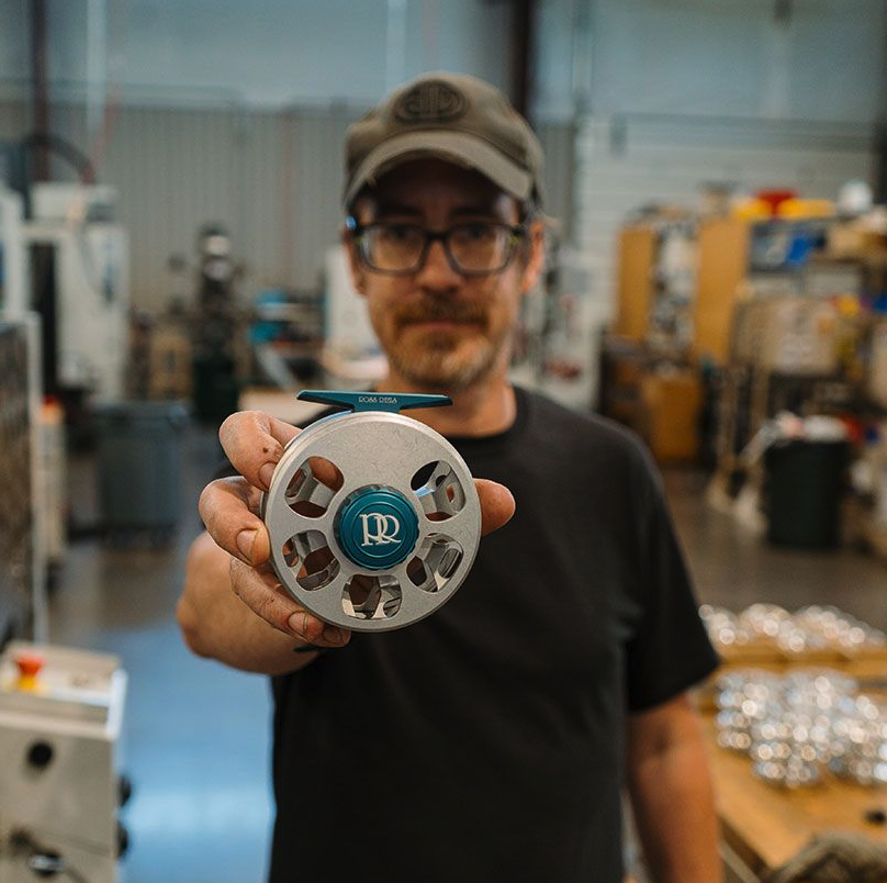 Machinist holding Ross Reels Cimarron Fly Reel Machinist Edition