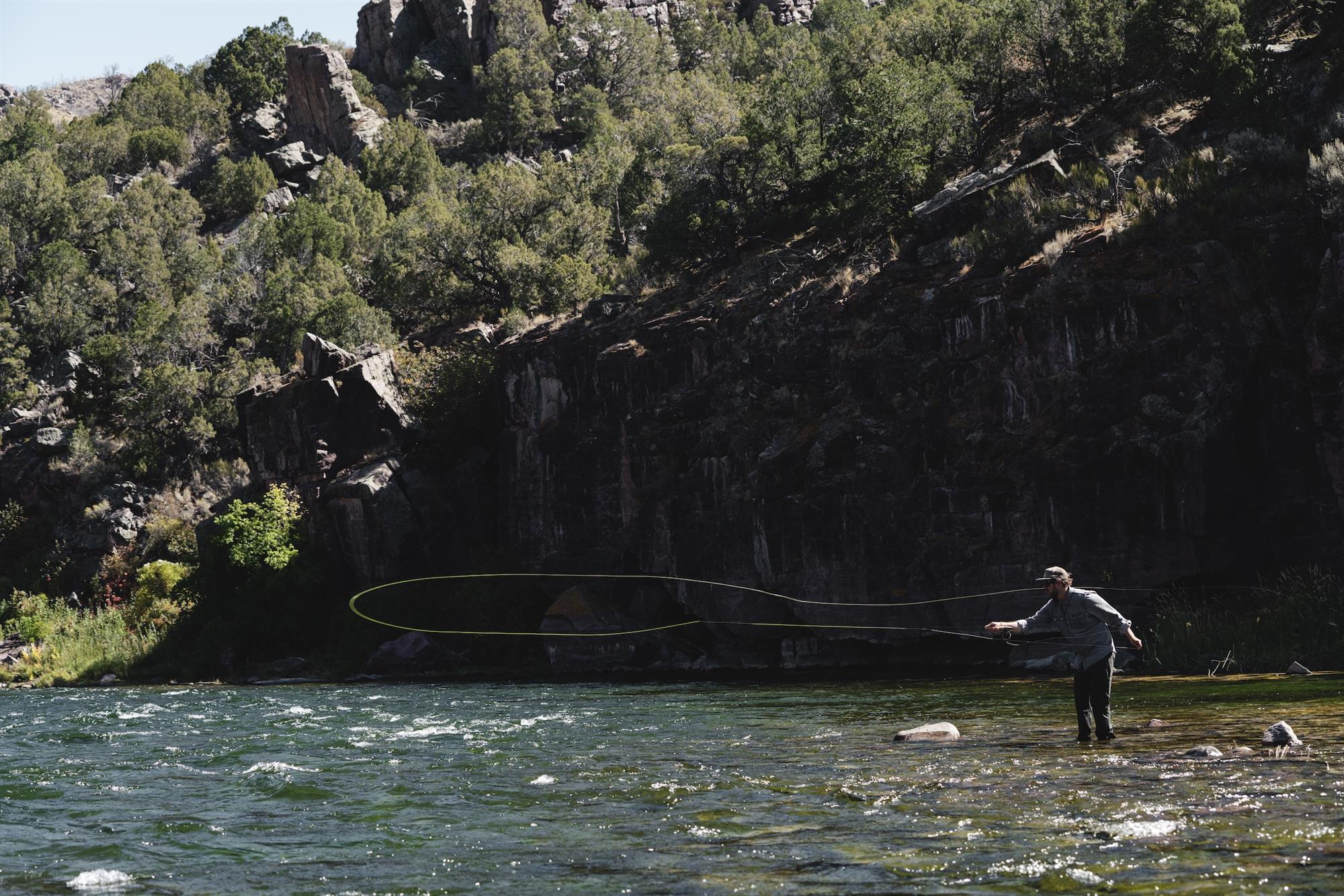 Angler casting in river with Sage ARROW Fly Rod